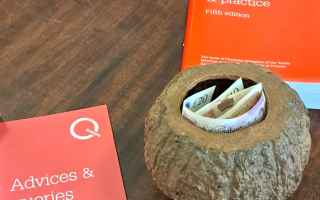 The hollowed out nut that Aylesbury Quakers use for collecting charity donations each Sunday. The Quaker books Advices and Queries; and Quaker Faith and Practice lie next to it.