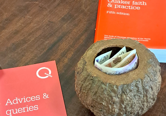 The hollowed out nut that Aylesbury Quakers use for collecting charity donations each Sunday. The Quaker books Advices and Queries; and Quaker Faith and Practice lie next to it.