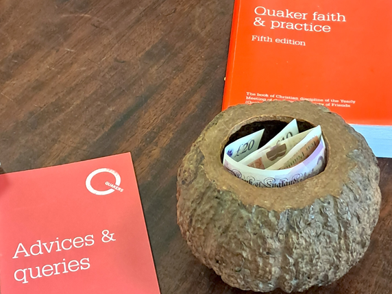 The hollowed out nut that Aylesbury Quakers use for collecting charity donations each Sunday. The Quaker books Advices and Queries; and Quaker Faith and Practice lie next to it.